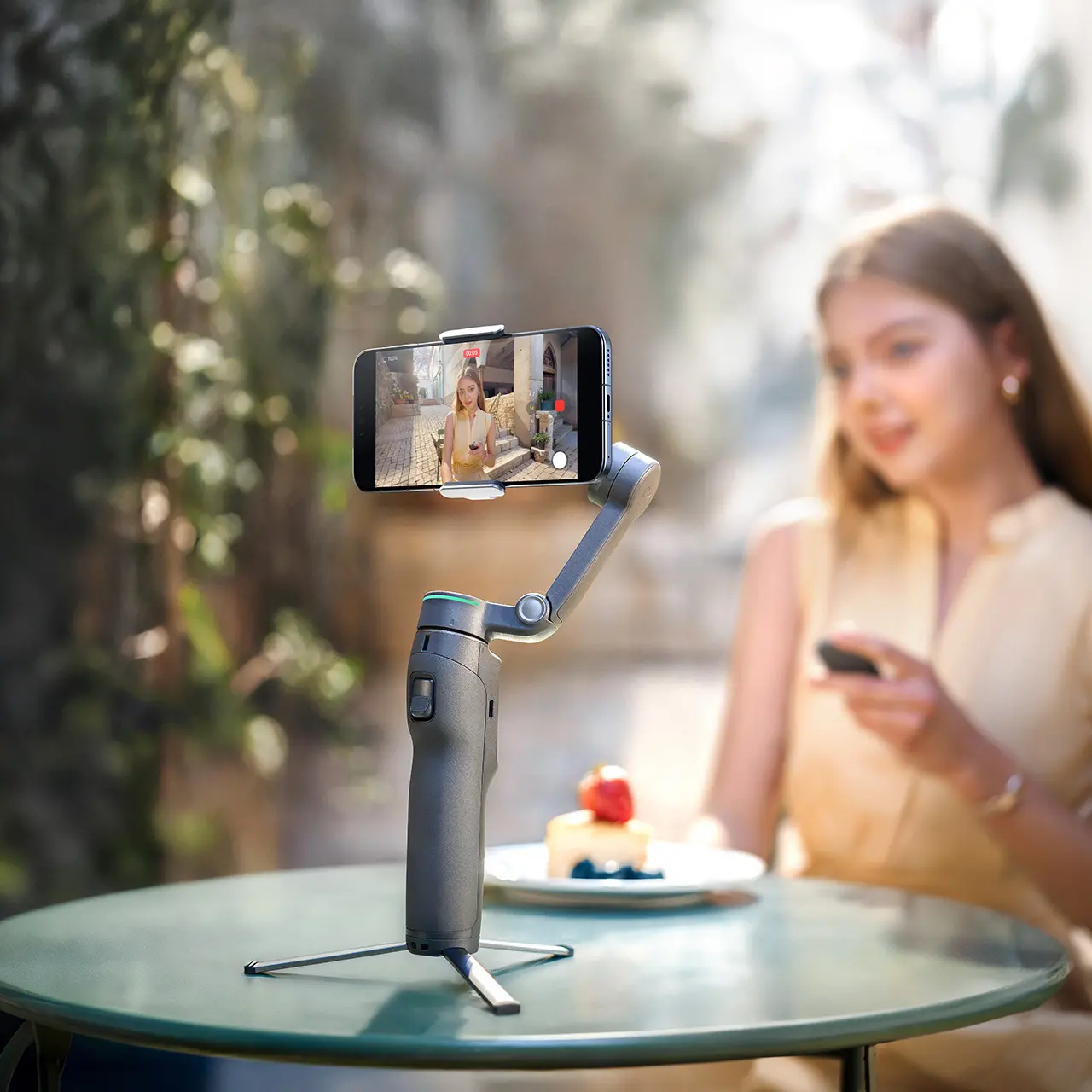 alt="Stabilisateur DJI Osmo Mobile 8P sur trépied avec smartphone pour vlog en extérieur et télécommande FrameTap