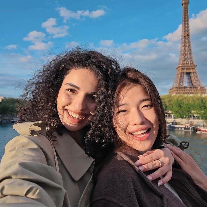 Photo prise avec la DJI Osmo Pocket 4P de deux personnes souriantes devant la tour Eiffel à Paris, mettant en valeur la qualité d'image, les couleurs naturelles et la netteté en extérieur.